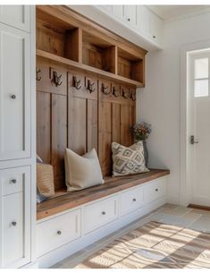 a wooden bench sitting in the middle of a room next to a white cabinet and door