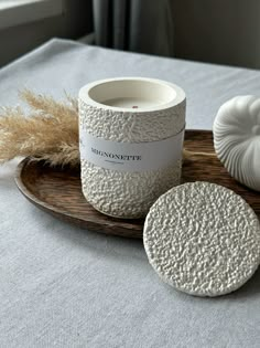 a white candle sitting on top of a wooden tray