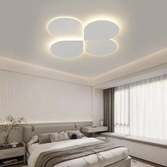 a bedroom with white walls and ceiling lights above the bed, along with a large window