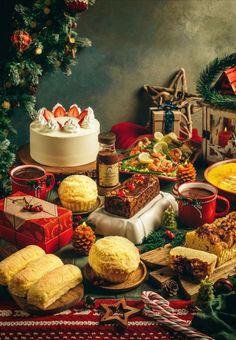 a table topped with lots of cakes and pies next to a christmas tree filled with presents