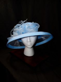 Sky Blue Symphony Derby Hat - Serene, Harmonious, Elegant This elegant derby hat is a perfect blend of femininity and sophistication. Its soft sky blue hue and intricate design create a captivating look. Sky Blue Color: A serene and calming color that adds a touch of elegance. Intricate Design: A beautiful, eye-catching piece with delicate details. Premium Materials: Crafted with high-quality materials for durability and comfort. Versatile Styling: Can be worn in various ways to suit your style. Make a Statement Today! Elevate your style with this unique accessory--shop now and turn heads at your next event! Fitted Blue Brimmed Top Hat, Blue Adjustable Fedora For Kentucky Derby, Fitted Blue Boater Hat With Curved Brim, Blue Wide Brim Fedora For Kentucky Derby, Fitted Blue Brimmed Fedora, Blue Fedora For Summer Parties, Blue Short Brim Boater Hat For Spring, Fitted Blue Brimmed Sun Hat, Blue Summer Fedora For Parties