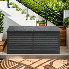 an outdoor storage box sitting on top of a wooden deck next to potted plants