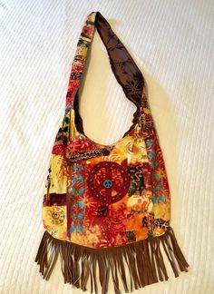 "Super cool. 100% up-cycled, cross-body shoulder bag! Exterior of this bag is multi colored corduroy, colors of red, brown, orange, yellow, gold, and turquoise. Brown sued fringe across the bottom, red felt peace sign with wooden  turquoise and copper beads. 2 tiny pockets on the back of the bag. Closes with a cocnut shell bead and brown satin ribbon. The interior is brown embossed velvet, with a beautiful daisy design! Stitched into the strap are the words \"Love and compassion are necessities, Hippie Multicolor Shoulder Bag With Adjustable Strap, Multicolor Hippie Hobo Bag, Multicolor Fringe Bags For Festival, Bohemian Multicolor Hobo Bag With Adjustable Strap, Red Bohemian Shoulder Bag With Tassels, Hippie Brown Hobo Bag For Festivals, Brown Hobo Bag For Festival, Bohemian Yellow Shoulder Bag With Adjustable Strap, Hippie Style Brown Hobo Bag For Festivals