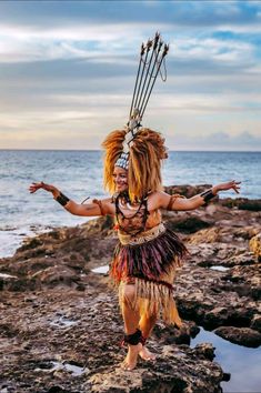 a man in costume standing on rocks near the ocean with his arms out and hands outstretched