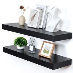 two black floating shelves with pictures and vases on each shelf, one is empty