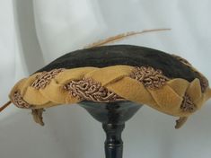 Simply a delightful and rare hat.  This Tilt hat is meant to wear, well tilted - to the side or front.   The crown is black and the exterior band is a beautiful weave of fancy brocade and flat marigold felt. It has two wire clips covered in the same material marigold interior band.  The graceful slim feather is 12.5 inches and starts at the broach and curves across the font. The broach crystals have been completely replaced because  the original was missing a few pieces. Please look closely at the last picture. The interior appears to have a large water mark that does not show through to the exterior. Pre-owned: no tears, stains or holes (see last photo) Crown Circumference 22.5 inches Crown depth 4.5 inches Brim depth 1.75 inches  All my items come from my clean smoke free home. Thank you Gold Leaf Bill Hat, Adjustable Felt Hat With Short Brim For Costume, Vintage Adjustable Fascinator With Structured Crown, Adjustable Costume Bonnet, Victorian Cloche Hat For Vintage Events, Victorian Cloche Hat For Evening, Victorian Brimmed Costume Hats And Headpieces, Victorian Brimmed Costume Hat, Victorian Curved Brim Costume Hat