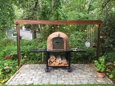 an outdoor pizza oven in the middle of a garden with string lights strung around it