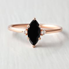 a black diamond ring with three diamonds on the side and an oval shaped stone in the middle