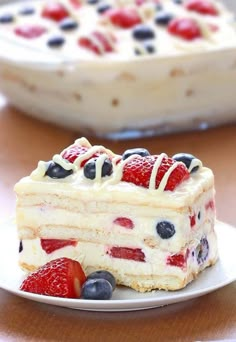 a piece of cake with berries and blueberries on it sitting on a plate next to another slice