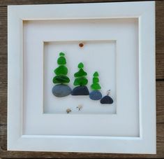 a white frame with green and blue rocks in the shape of trees on top of it