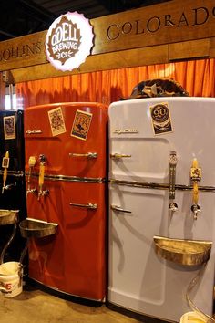 two old fashioned refrigerators are on display in a showroom with orange drapes