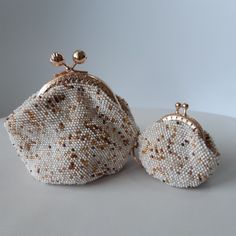 two white and gold beaded purses sitting next to each other