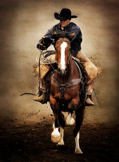 a man riding on the back of a brown and white horse in a dirt field