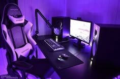 a computer desk with a keyboard, mouse and monitor in front of a purple light