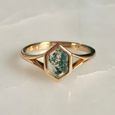 a gold ring with a green stone in the center on a white surface, close up