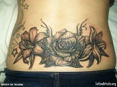 a woman's lower back tattoo with flowers on her stomach and the bottom half