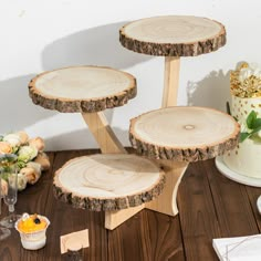 three tiered cake stand made out of wood slices on a wooden table with flowers in the background