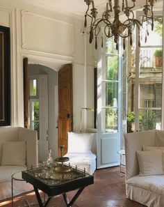 a living room filled with white furniture and a chandelier hanging from the ceiling