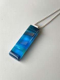 "Colorful waves of aqua, sea blue and turquoise glass combine with shimmery bands of dichroic and iridescent glass to create the impressionistic pendant on this necklace. The depth and variety of colors in the glass create a striking, one-of-a-kind kiln-fired pendant. Glass is kiln fired, shaped with beveled edges, and then fire polished in my glass studio. Pendant hangs from a sterling silver bail on a sterling silver bead chain. Pendant is also available in green, olive green, cobalt blue, bla Colorful Waves, Ocean Resin, Glass Garden Art, Glass Studio, Art Ocean, Turquoise Glass, Green Olive, Bubble Glass, Bead Chain