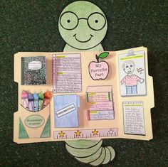 a paper cut out of a caterpillar holding an apple and some school supplies