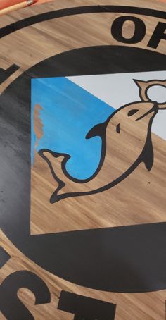 a close up of a wooden sign with a dolphin on it