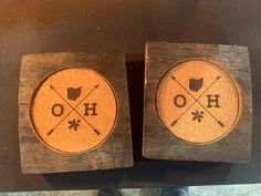 two wooden coasters with the words hoo and crossed arrows on them are sitting on a table