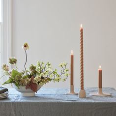 a table topped with two candles and a bowl filled with flowers