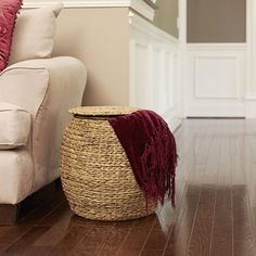 a white couch sitting next to a wooden floor in front of a red throw pillow