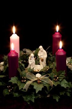 three candles are lit in the middle of a wreath with two figurines on it