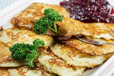 a plate topped with pancakes covered in toppings and cranberry sauce next to a fork