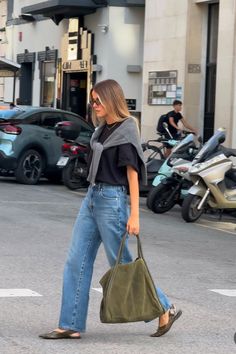 a woman is walking down the street carrying a handbag in her right hand and looking back