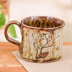 a coffee cup sitting on top of a wooden table next to a green leafy plant