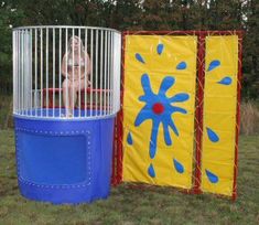 a woman sitting on top of a blue and yellow birdcage