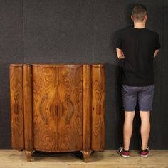 a man standing next to a wooden cabinet