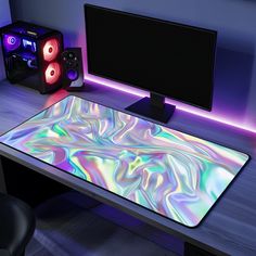 a computer desk with speakers and a colorful mouse pad sitting on it's side