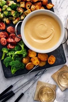 broccoli, potatoes and other foods on a cutting board with utensils