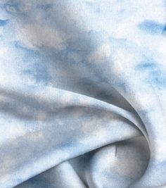 a blue and white tie dyed fabric with clouds in the sky on it's side