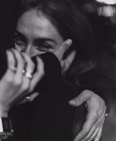 a black and white photo of a woman holding her hand up to her face while looking at the camera