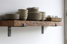 some plates and bowls are sitting on a shelf with brackets to hold them in place