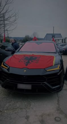 a black sports car with a red eagle on it's hood parked in a parking lot