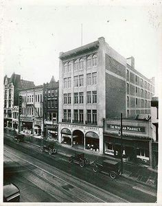 an old black and white photo of a city street with cars driving down the road