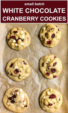 six cookies with white chocolate chips and cranberries on top, lined up on parchment paper