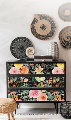 a dresser with flowers painted on it in front of baskets and wall hangings above