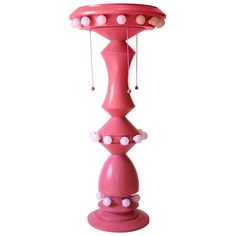 a pink lamp with white polka dots on the top and bottom, hanging from it's base