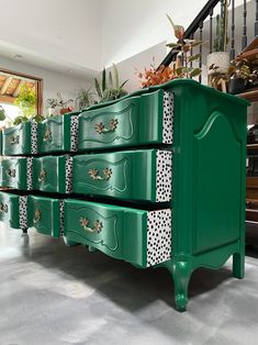 a green chest of drawers with polka dots painted on the top and bottom, sitting in front of a staircase