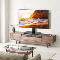 a flat screen tv sitting on top of a wooden entertainment center in a living room