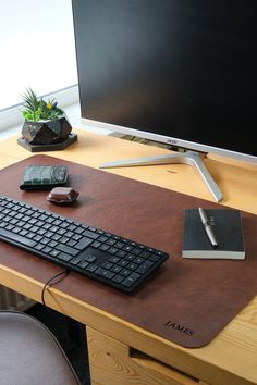 a desk with a keyboard, mouse and cell phone on it next to a monitor