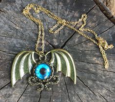 Gothic necklace shaped like a winged blue eyeball on a 20 inches long golden-tone metal chain with a lobster claw clasp. Eyeball With Wings, Flying Eyeball, Wings Necklace, Gothic Necklace, Metal Chain, Necklace Pendant, Lobster Claw, Pendant Necklaces, Turquoise Necklace