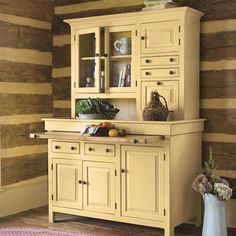 an old fashioned kitchen with yellow cabinets and wood paneling on the wall behind it