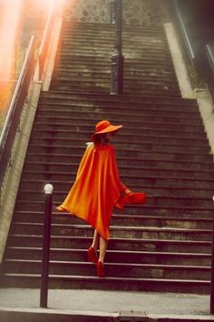 a woman in an orange cape is walking down some stairs